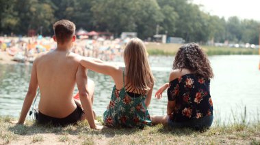 Üç arkadaş açık havada eğleniyor. Gölde bir gün zevk gençler. Arkadan Görünüş.