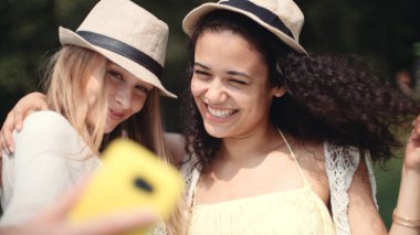 İki neşeli kız selfies bir gölün yanında yapma. Kız arkadaşlar selfie fotoğraf ile smartphone alarak. Gülümseyen iki genç kadın güzel tatil keyfi.