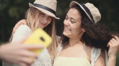 İki neşeli kız selfies bir gölün yanında yapma. Kız arkadaşlar selfie fotoğraf ile smartphone alarak. Gülümseyen iki genç kadın güzel tatil keyfi.