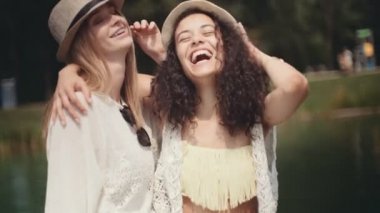 Bir göl kenarında vakit iki neşeli kız. İki genç kadın tatil zevk gülümseyen.