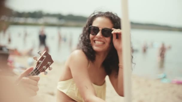 穿着比基尼的年轻女子的肖像坐在海滩上的朋友和微笑 — 图库视频影像