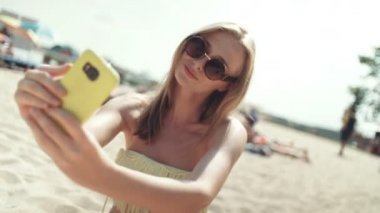 Sahilde oturan ve bir selfie alarak bikinili güzel kadın.