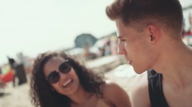 Arkadaş grubu sahilde oturan ve gülümseyen Bikini genç kadın portresi.