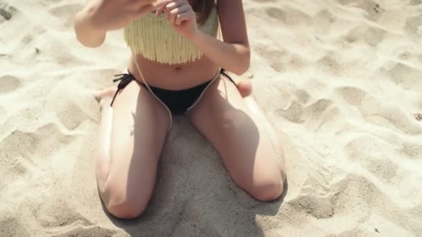 Νεαρή Ξανθιά Γυναίκα Που Κάθεται Στην Παραλία Χαμογελώντας — Αρχείο Βίντεο