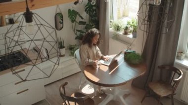 Sevimli genç kadın dizüstü bilgisayarda bir mutfak tipik.