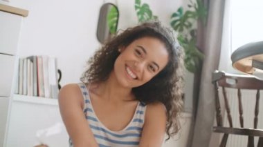 Bir yerde otururken kameraya gülümseyen güzel bir genç kadının portresi.