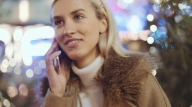 Avrupa Noel piyasasında Smartphone kullanan kadın. Noel, sosyal ağ ve iletişim kavramı. Arka plan bulanık Noel ışıkları.