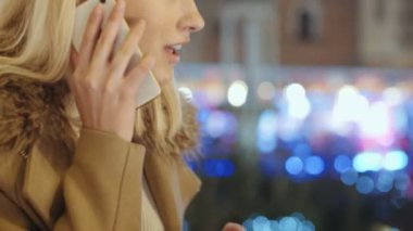 Avrupa Noel piyasasında Smartphone kullanan kadın. Noel, sosyal ağ ve iletişim kavramı. Arka plan bulanık Noel ışıkları.