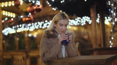 Mutlu çekici kadın sıcak içme bir Noel Pazar geceleri.