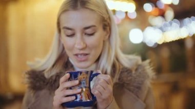 Mutlu çekici kadın sıcak içme bir Noel Pazar geceleri.