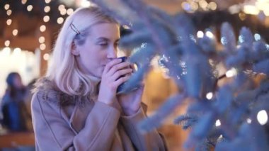 Mutlu çekici kadın sıcak içme bir Noel Pazar geceleri.