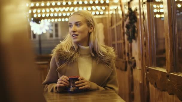 夜のクリスマス マーケットで飲み物を飲んで幸せな魅力的な女性 — ストック動画