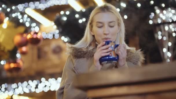 Ευτυχισμένος Ελκυστική Γυναίκα Πίνοντας Ζεστό Ρόφημα Μια Χριστουγεννιάτικη Αγορά Νύχτα — Αρχείο Βίντεο