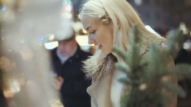 Genç sarışın kız eğleniyor bir şehirde Noel pazarında.