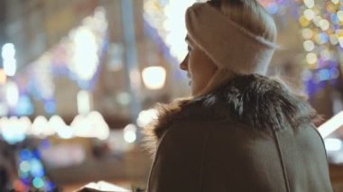 Bir şehirde Noel pazarında genç gülümseyen kadın portresi.