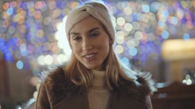 Bir şehirde Noel pazarında genç gülümseyen kadın portresi.