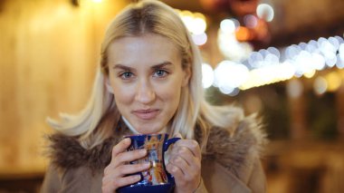 Mutlu çekici kadın sıcak içme bir Noel Pazar geceleri.