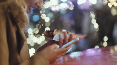 Kadın elinde telefon kullanarak kapatın. Cep telefonuyla bir şehirde gece genç kadın.