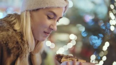 Noel pazarı üzerinde akıllı telefon kullanan kadın. Çikolata ile gözleme bir Noel Pazar geceleri yemek mutlu çekici kadın. Güzel bokeh ışıklar arka plan.