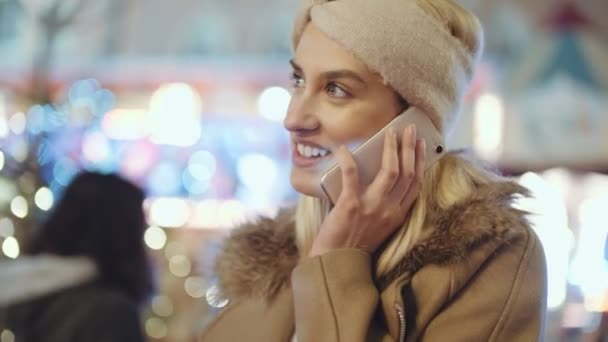 使用智能手机在欧洲圣诞市场的妇女 圣诞节的概念 社交网络和沟通 背景上模糊的圣诞灯 — 图库视频影像