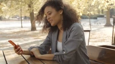 Cep telefonu, açık kullanarak siyah kıvırcık saçlı güzel genç kız.