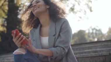 Cep telefonu, açık kullanarak siyah kıvırcık saçlı güzel genç kız.