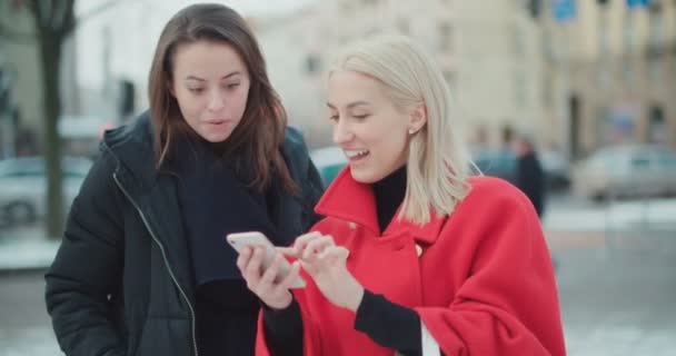 Dos Chicas Jóvenes Usando Teléfono Móvil Una Ciudad — Vídeos de Stock
