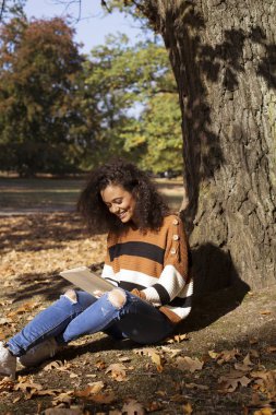 Tablet bilgisayar, açık kullanarak siyah kıvırcık saçlı güzel genç kız.