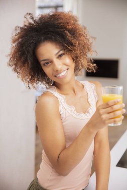 Mutlu karışık yarış kadın portakal suyu veya smoothie tutan ve kameraya bakıyor.