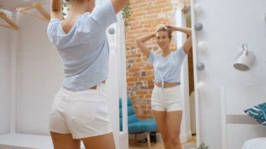 Kadın çalışıyor giysi ve ayna şaşırmayacağınıza mutlu bakıyor. 