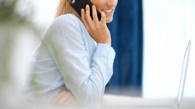 Evde akıllı telefon kullanan genç bir kadın..