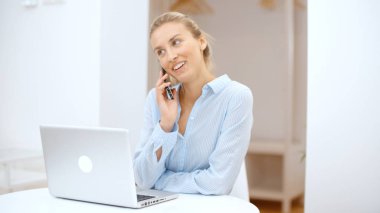 Evde akıllı telefon kullanan genç bir kadın..