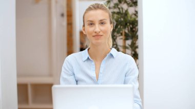 Evde bilgisayarla çalışan genç sarışın kadın..