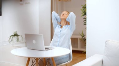 Evde bilgisayarla çalışan genç sarışın kadın..