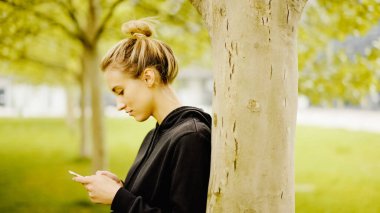 Şehir parkında telefon kullanan çekici bir kadın..