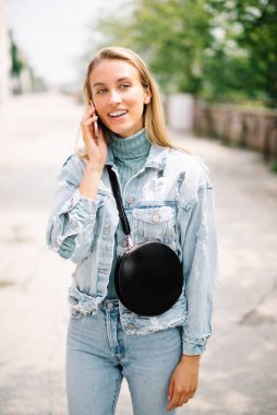 Telefon bir şehirde kullanan genç sarışın kadın.