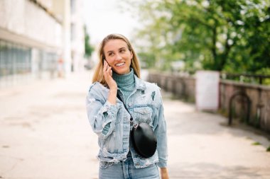 Telefon bir şehirde kullanan genç sarışın kadın.