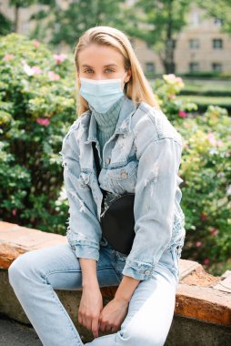 Şehirde antibakteriyel maske takan genç bir kadının portresi.