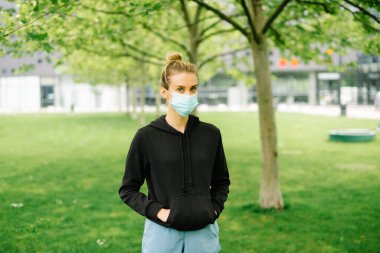 Şehirde antibakteriyel maske takan genç bir kadının portresi.