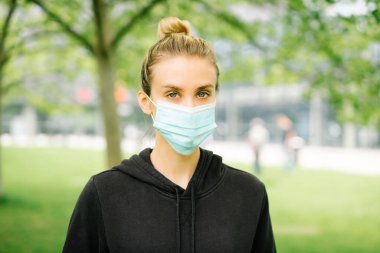 Şehirde antibakteriyel maske takan genç bir kadının portresi.