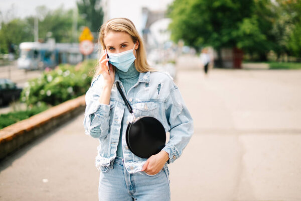 Young woman wearing antibacterial mask using phone in a city.