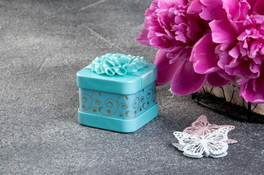 Pembe şakayık, Akuamarin hediye kutusu ve kelebekler gri dokulu arka plan üzerine kapatalım. Doku metin için beton ve kopya alanı