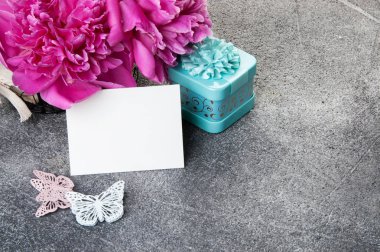 Pembe şakayık, boş Not, Akuamarin hediye kutusu ve kelebekler gri dokulu arka plan üzerine kapatalım. Doku metin için beton ve kopya alanı