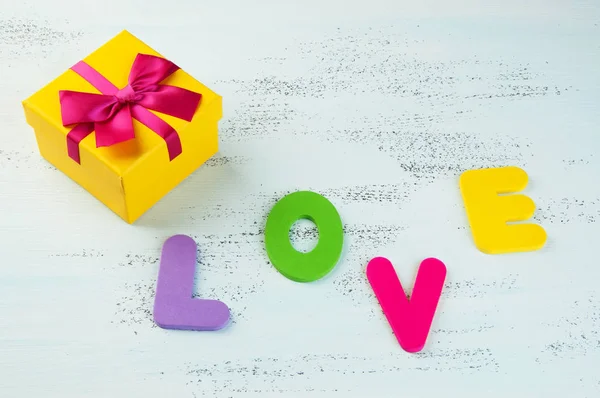 Желтая Подарочная Коробка Луком Словом Любовь Выложена Разноцветными Буквами Потрепанном — стоковое фото