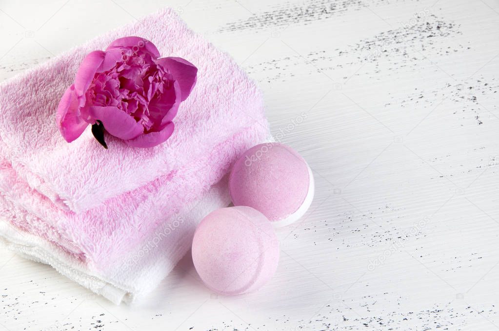 Pink white SPA composition with bath bombs, pink peony and towels on shabby white textured background. Copy space for text