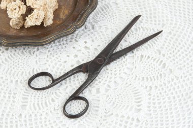 Eski vintage makas ve vintage metal plaka ile kuru gül beyaz tığ işi bardak altlığı peçete üzerinde. Cpace metin kopyalama.