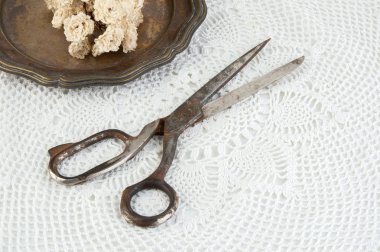 Eski vintage makas ve vintage metal plaka ile kuru gül beyaz tığ işi bardak altlığı peçete üzerinde. Cpace metin kopyalama.