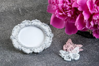 Pembe şakayık, eski püskü fotoğraf çerçevesi ve kelebekler gri dokulu arka plan üzerine kapatalım. Doku metin için beton ve kopya alanı