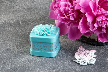 Pembe şakayık, Akuamarin hediye kutusu ve kelebekler gri dokulu arka plan üzerine kapatalım. Doku metin için beton ve kopya alanı