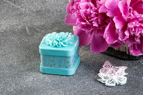 Pembe şakayık, Akuamarin hediye kutusu ve kelebekler gri dokulu arka plan üzerine kapatalım. Doku metin için beton ve kopya alanı